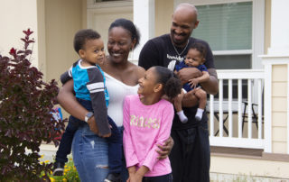 Photo of smiling family in front of Genevieve property